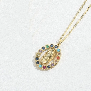 Detailed close-up of a gold oval Virgin Mary pendant with multi-colored gemstone inlay