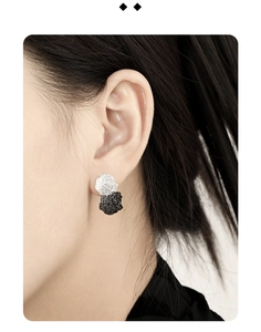 Detailed close-up of S925 sterling silver studs with textured black and silver discs