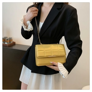 Detailed close-up of yellow quilted chain bag with gold metal trim and textured leather