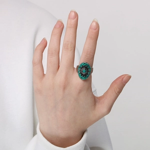 Close-up of bohemian oval ring with turquoise stone and embossed metal on model's hand