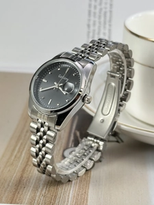 Detail of silver stainless steel watch with black dial and date window on stand