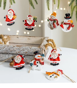 Detail of Christmas snowman and Santa ornaments hanging on green pine branches