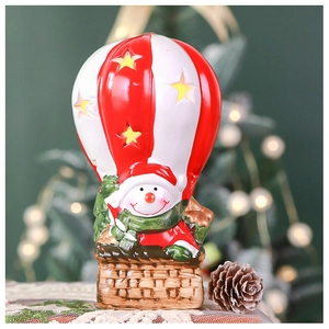 Close-up of lighted snowman hot air balloon ornament with star cutouts and festive bokeh