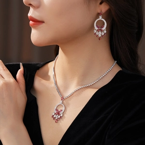 Detail of butterfly necklace and earrings set with red stones on model's neck
