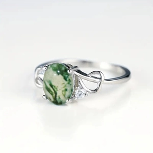Detailed shot of moss agate ring with silver heart-shaped cutout and oval green gemstone