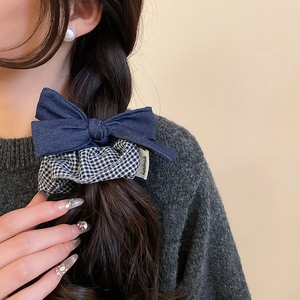 Detail of dark blue denim bow scrunchie with black and white grid pattern on hair