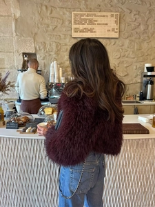 Λεπτομερής υφή από γυναικείο κοντό παλτό από συνθετική γούνα σε σκούρο κόκκινο χρώμα