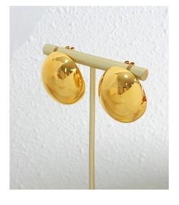 Macro view of polished gold teardrop stud earrings on a T-bar jewelry display stand