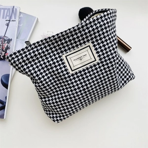 Chic houndstooth makeup bag detail with cosmetic brushes and lipstick on a stylish background