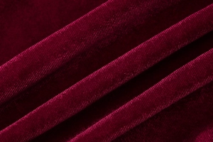Macro shot of burgundy velvet fabric texture with fine vertical stripes and soft luster