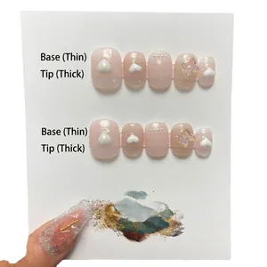 Pink press-on nail set with white hearts and bows featuring gradient thickness