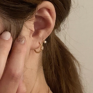 Close-up of elegant gold plated silver earrings with white zircon and a pearl detail