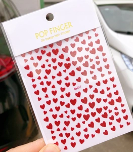 Detail of 3D nail stickers featuring sparkling red glitter hearts in various sizes