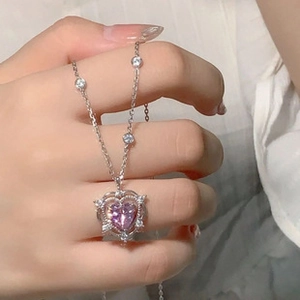 Macro shot of a silver necklace featuring a heart-shaped purple gem and zircon fringe detail