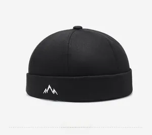 Detail shot of mountain peak embroidery on a black cotton docker cap with rolled cuff