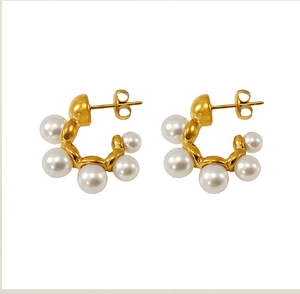 Detail view of gold C-shaped earrings with five round white pearls and metal plating