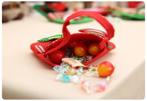 Close-up of a festive red fabric Christmas gift bag filled with colorful candies and berries