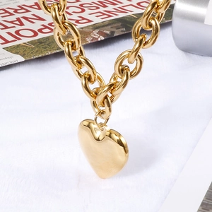 Polished gold thick chain necklace with a large heart pendant on a white background