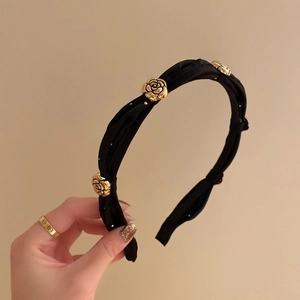 Elegant black fabric headband featuring decorative gold camellia flowers held by a model