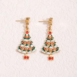 Macro detail of enamel Christmas tree earrings with gold star studs on a beige backdrop