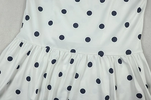 Detail of black polka dot print on cream fabric with waist pleats and soft draping