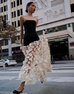 Detailed close-up of 3D floral petals on a mesh skirt of an elegant black evening gown