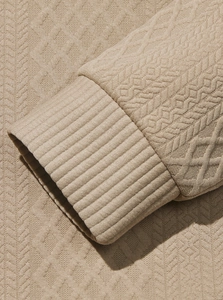 Detailed macro view of the textured jacquard fabric and ribbed cuff on men's beige sweatshirt