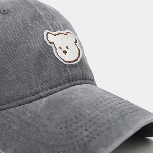 Close-up of cute white bear embroidery and stitching on dark gray cotton baseball cap