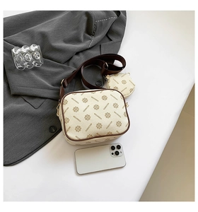 Close-up of beige crossbody camera bag with all-over print and round coin purse accessory