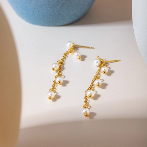 Detailed view of 18K gold stainless steel drop earrings with elegant white pearl clusters