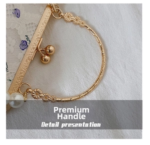 Detail view of gold circular metal handle with floral relief and large pearl charm