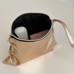 Close-up of golden snakeskin texture cosmetic bag with zipper and handle strap