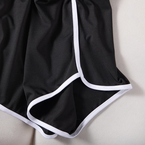 Detailed close-up of high-elastic black sports shorts with white contrast piping trim