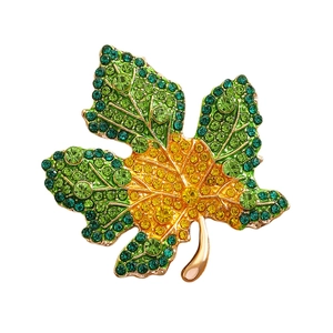 Detail of maple leaf brooch with green and yellow rhinestones on gold alloy base