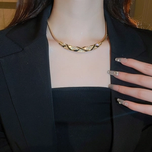 Close-up of vintage gold arched necklace with black enamel and diamonds on model