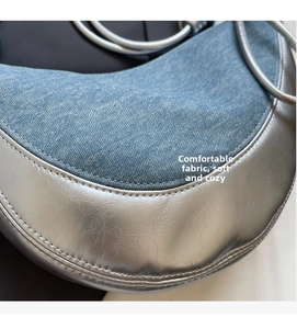 Detail of light blue denim fabric and silver metallic leather stitching on shoulder bag