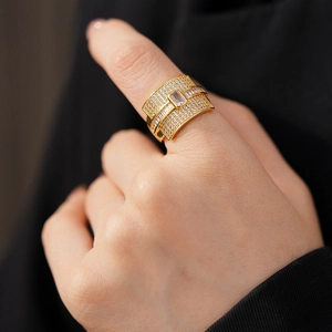 Detail of gold-plated wide ring with zircon pavé and rectangular center stone on finger