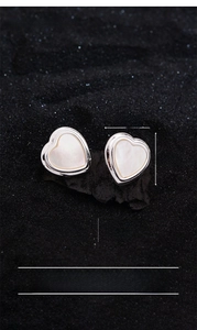 Detailed macro view of heart-shaped silver-plated earrings with white shell inlay