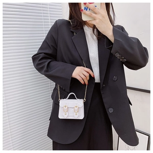 White jelly mini crossbody bag with metal chain shown on model in black suit