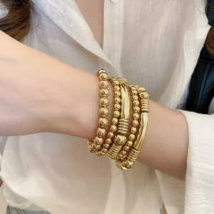 Vue détaillée d'un ensemble de cinq bracelets dorés avec perles métalliques et tubes lisses