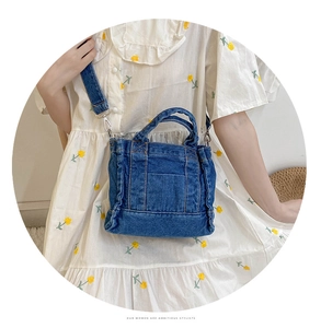 Close-up of a blue denim tote bag worn by a model in a natural outdoor setting