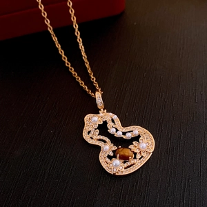 Vue détaillée du collier gourde en or avec œil de tigre, perles et zircons sur fond sombre