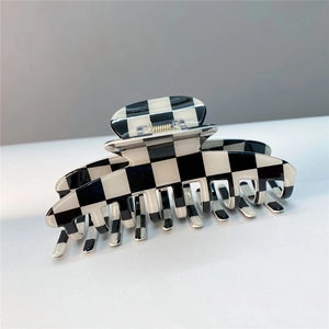 Detail shot of the sturdy metal spring and black and white checkerboard pattern hair claw