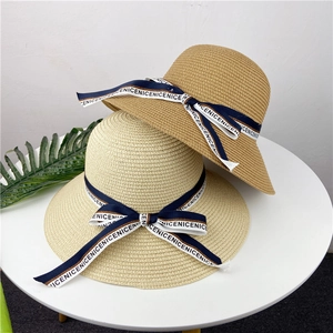 Détail de chapeaux de paille avec rubans bleu marine sur une table au style minimaliste