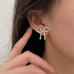 Sparkling S925 sterling silver bow knot stud earrings for women on a model's ear