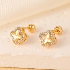 Golden clover and star ear studs with white cubic zirconia on a stone surface
