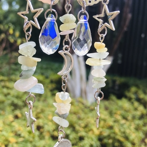 Detail of silver suncatcher with crystal prisms and natural quartz stones in garden