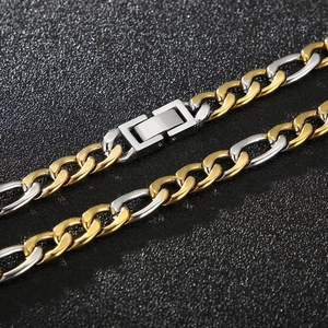 Chaîne Figaro bicolore or et argent avec fermoir pliable sur fond noir texturé élégant