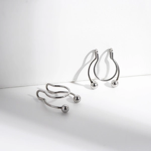 Macro detail of two silver U-shaped stainless steel nose clips with ball ends