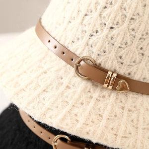 Detail of cream knit sun hat featuring brown leather belt and gold heart charm